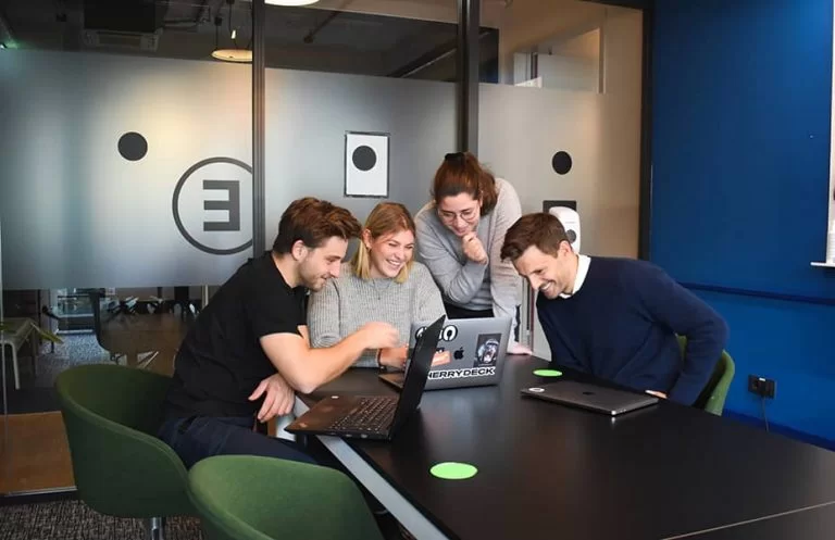 A team of 4 experts working together on a laptop