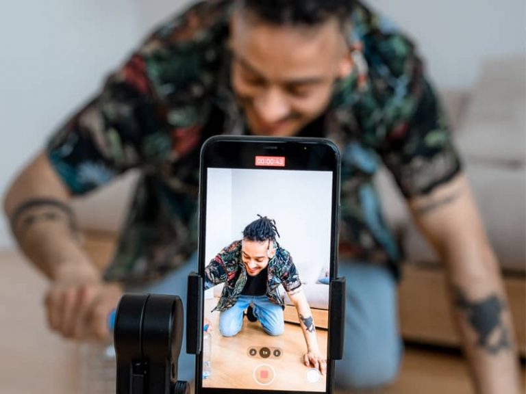A man doing a live video with the camera showing the man beding down on the ground with products