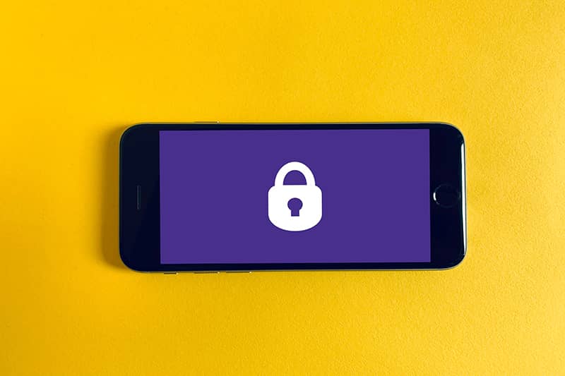 A mobile phone with a purple screen and white lock icon on a yellow background