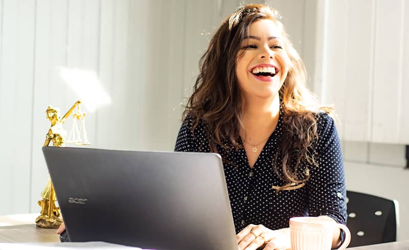 A lady sitting at her desk in front of her laptop smiling to a client