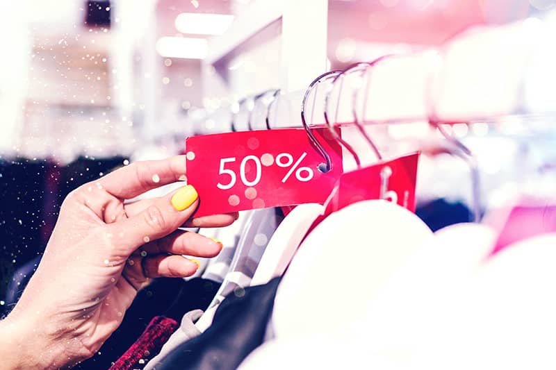 A 50% Discount tag on a clothing rack