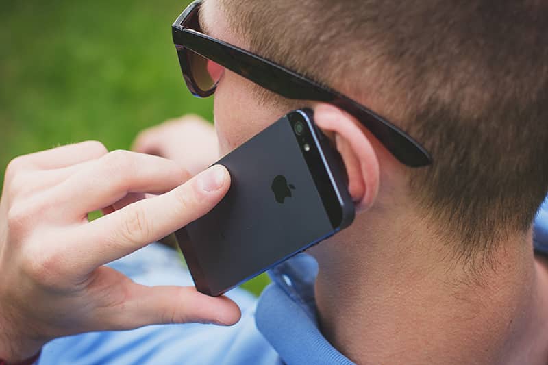 A man wearing glasses on his Apple iPhone