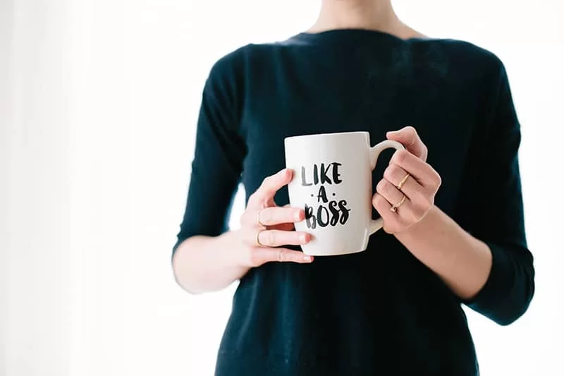 A lady holding a "Like a boss" coffee cup