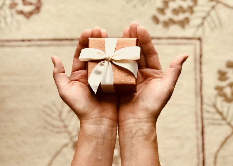 A person holding a small gift box in both hands