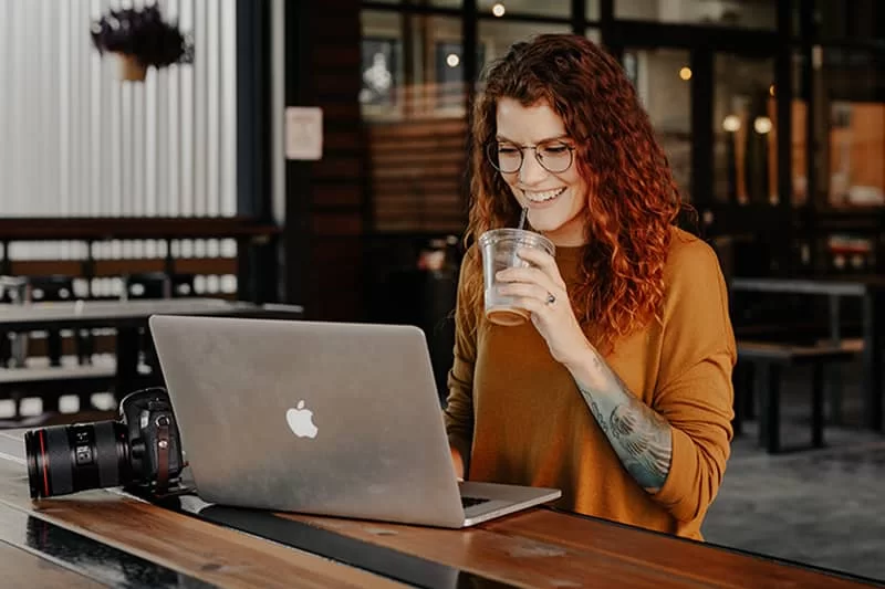 A web developer sitting in a cafe having a drink in front of her laptop