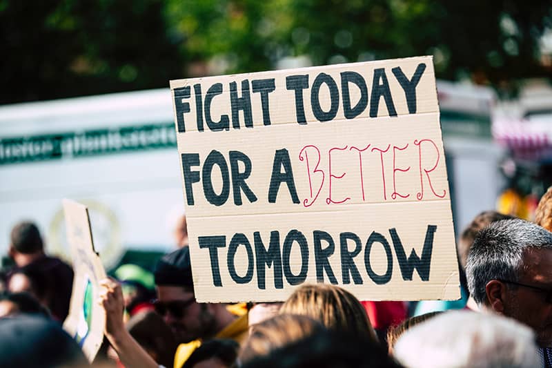 A person holding up a fight today for a better tomorrow sign