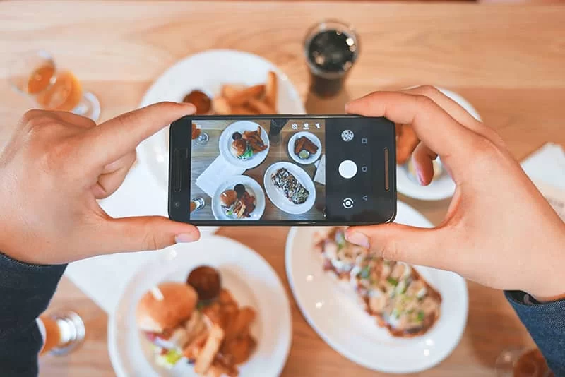 A mobile taking a picture of food on a table at a restaurant
