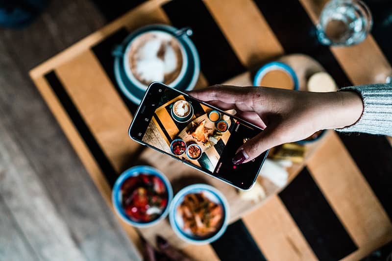 A phone taking photos of coffee and food