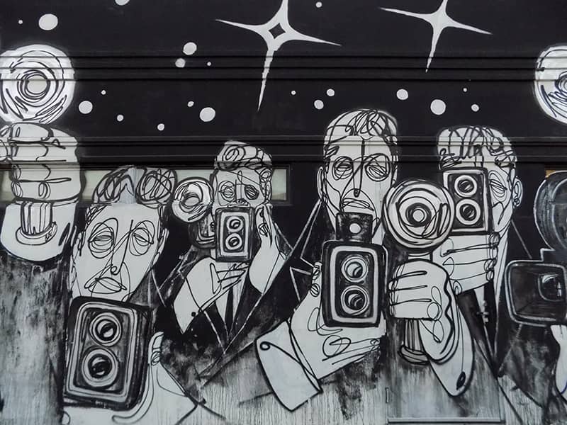 Street art of paparazi on a black wall