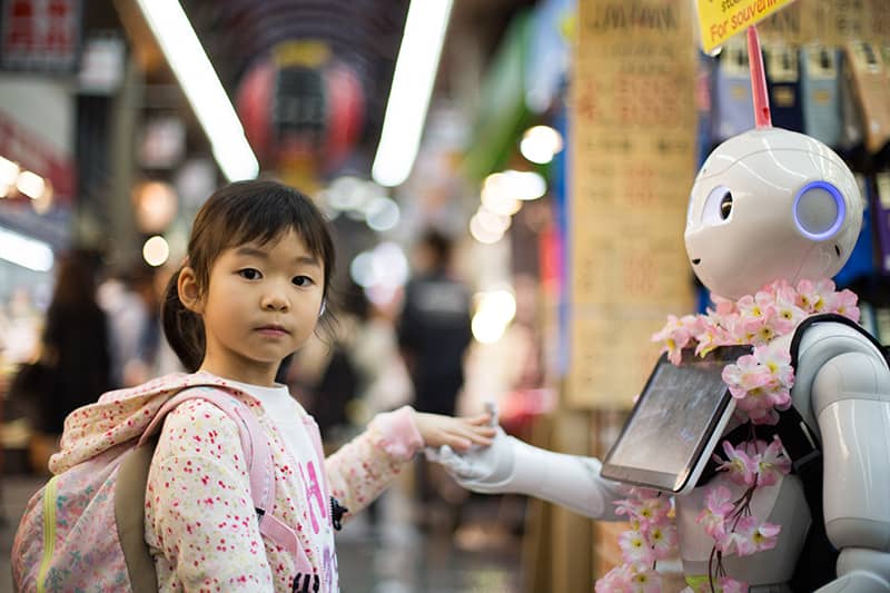 A young girl with her hand in a robots hand