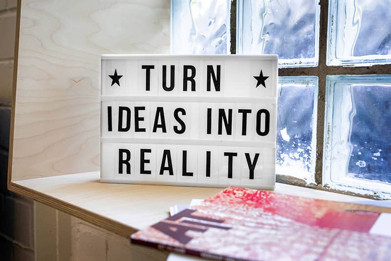 A light box with the words "Turn ideas into reality" written on it.