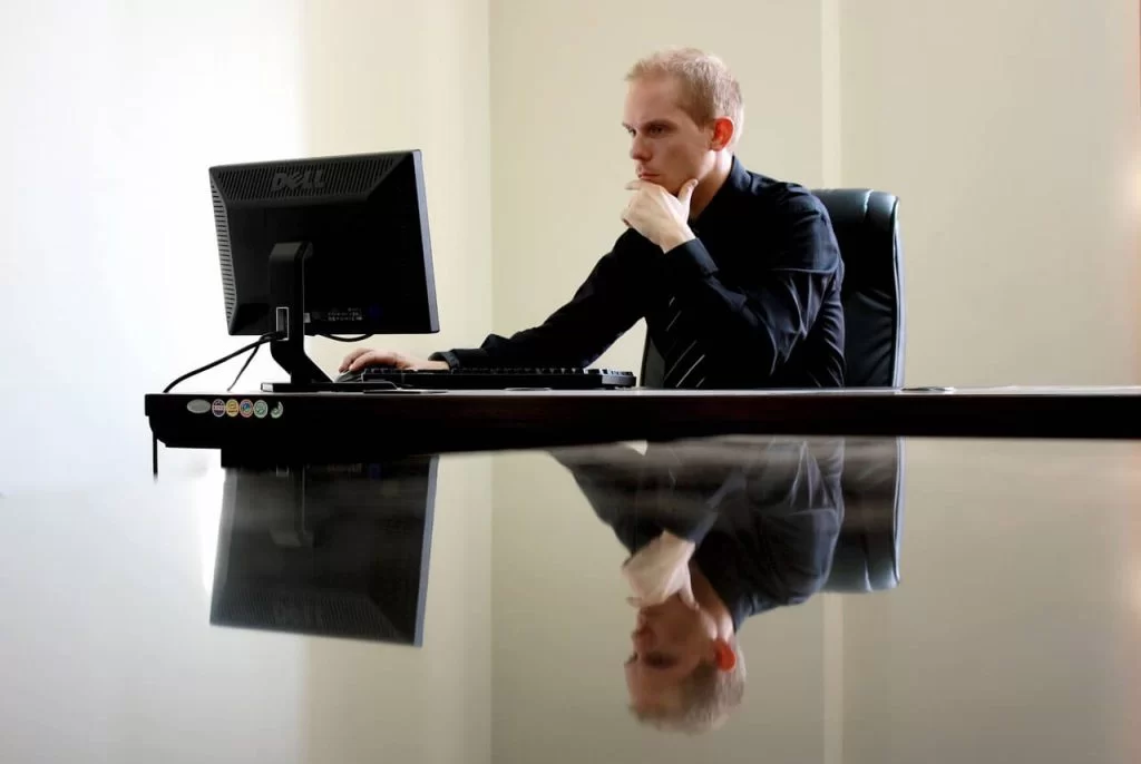A man sitting at his desk looking at his computer screen.