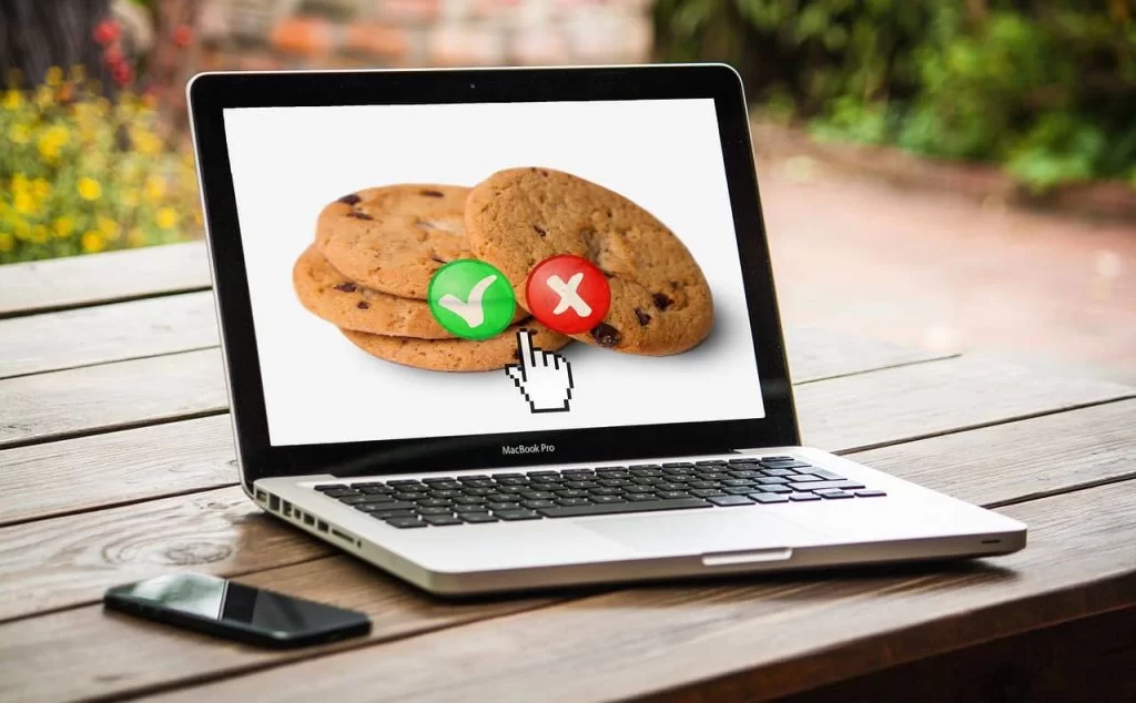 A laptop with a picture of cookies on the screen with a green tick button or red cross button as screen options.