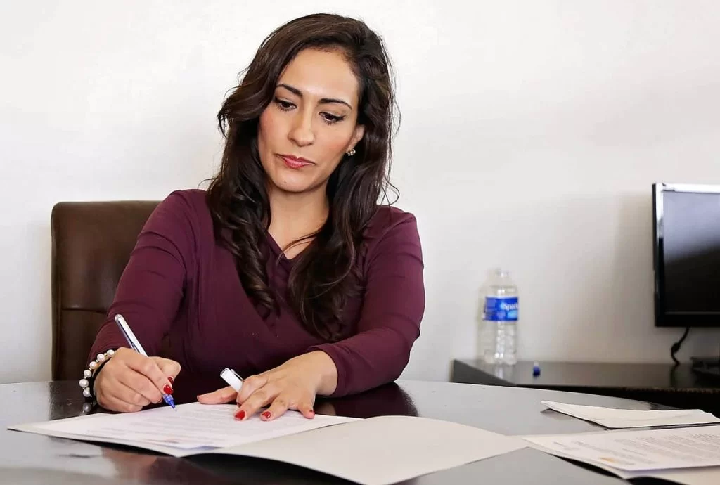 A lady sitting at her office desk signing some papers