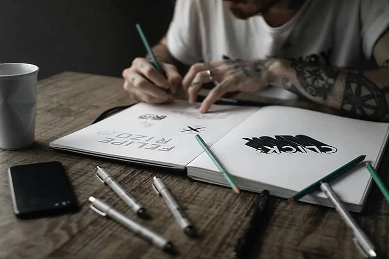 A logo designer creating logos in their book.