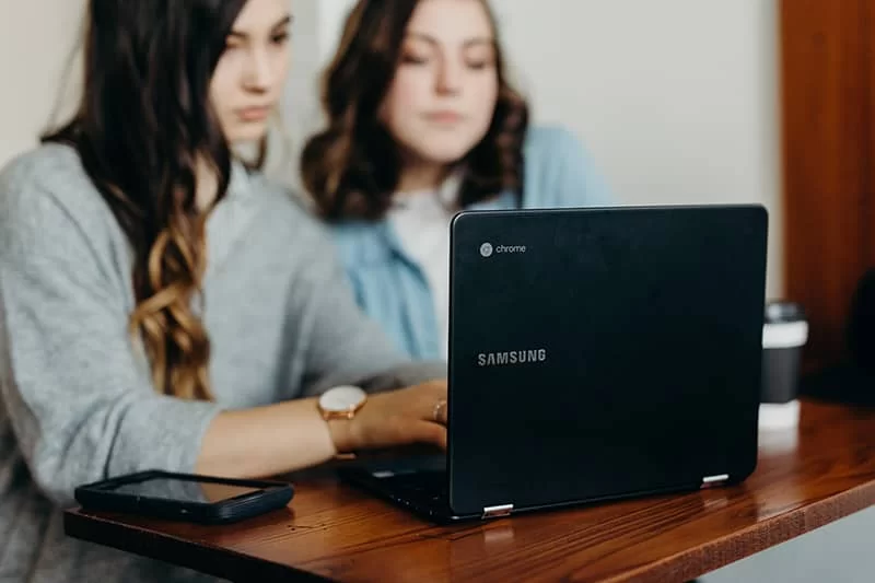 Two girls looking at a laptop screen.