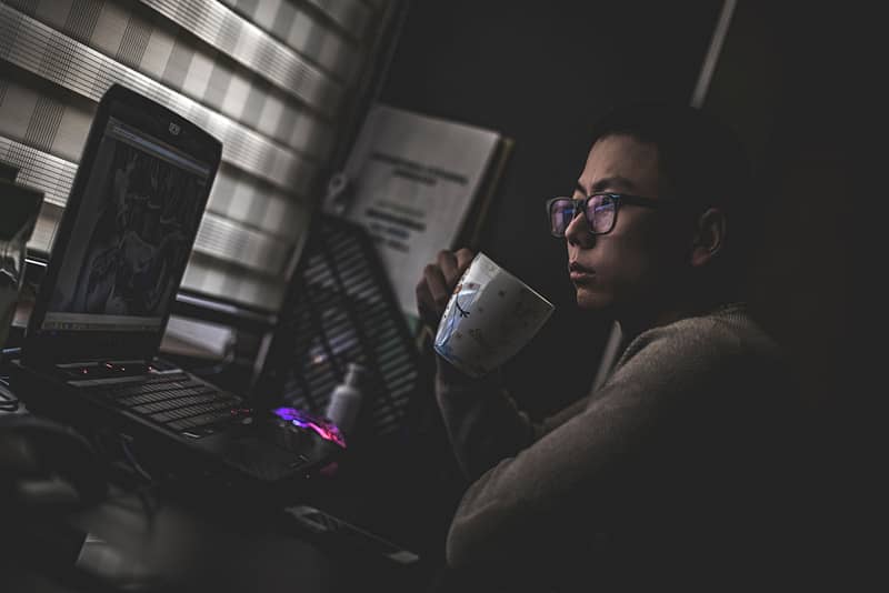 A web developer with a coffee in their hand looking at a monitor